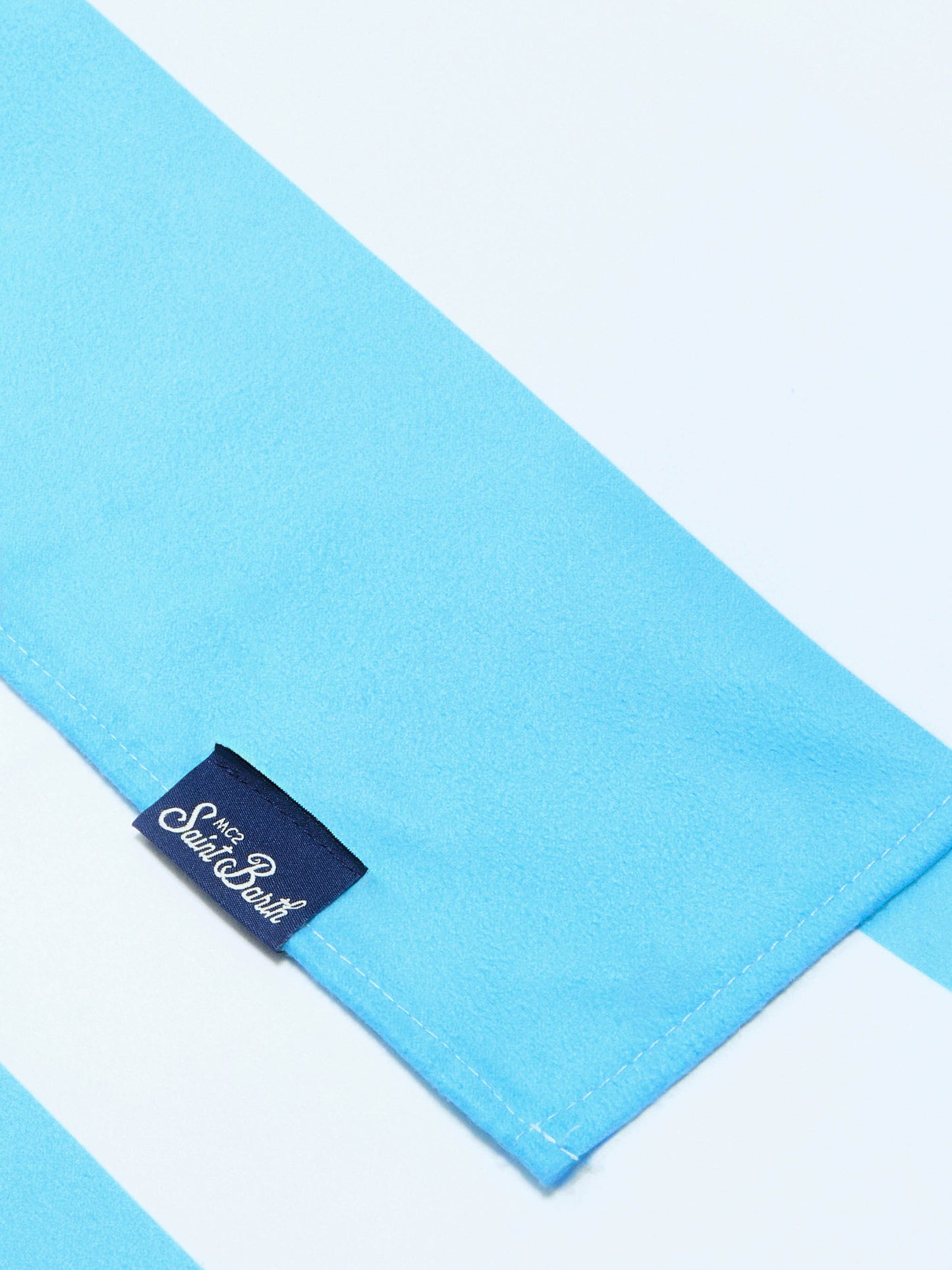 Aidan beach towel with light blue and white stripes and logo